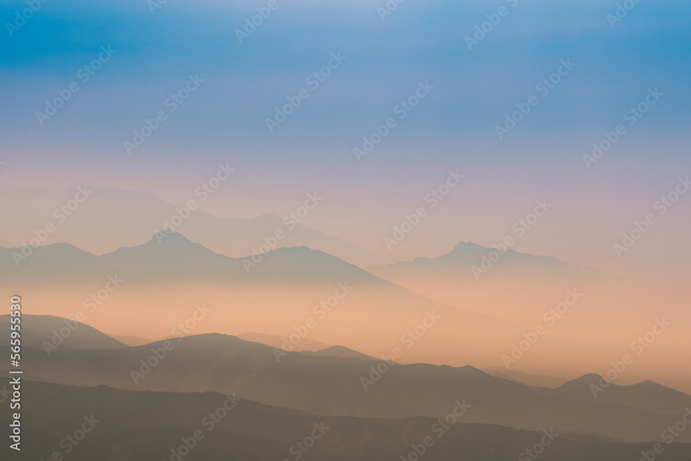 A magical dawn over the Caucasus Mountains with layers of mountain ranges and a blue sky