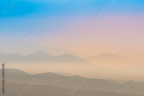 A magical dawn over the Caucasus Mountains with layers of mountain ranges and a blue sky