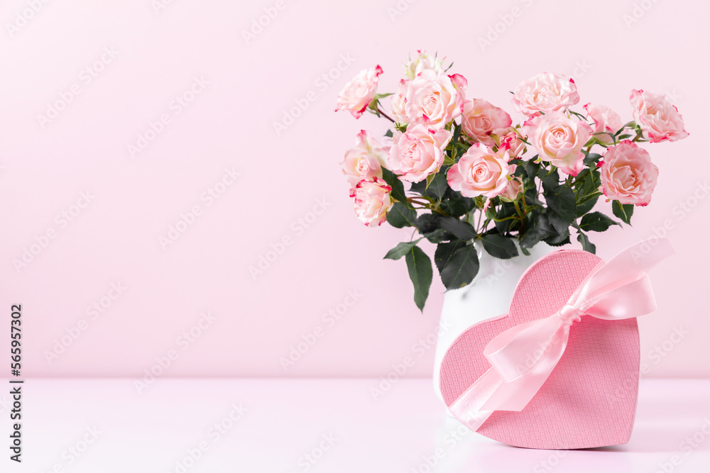 Obraz premium Beautiful bouquet flowers pink roses in vase and gift box with satin bow on pastel pink background table. Birthday, Wedding, Mother's Day, Valentine's day, Women's Day. Front view