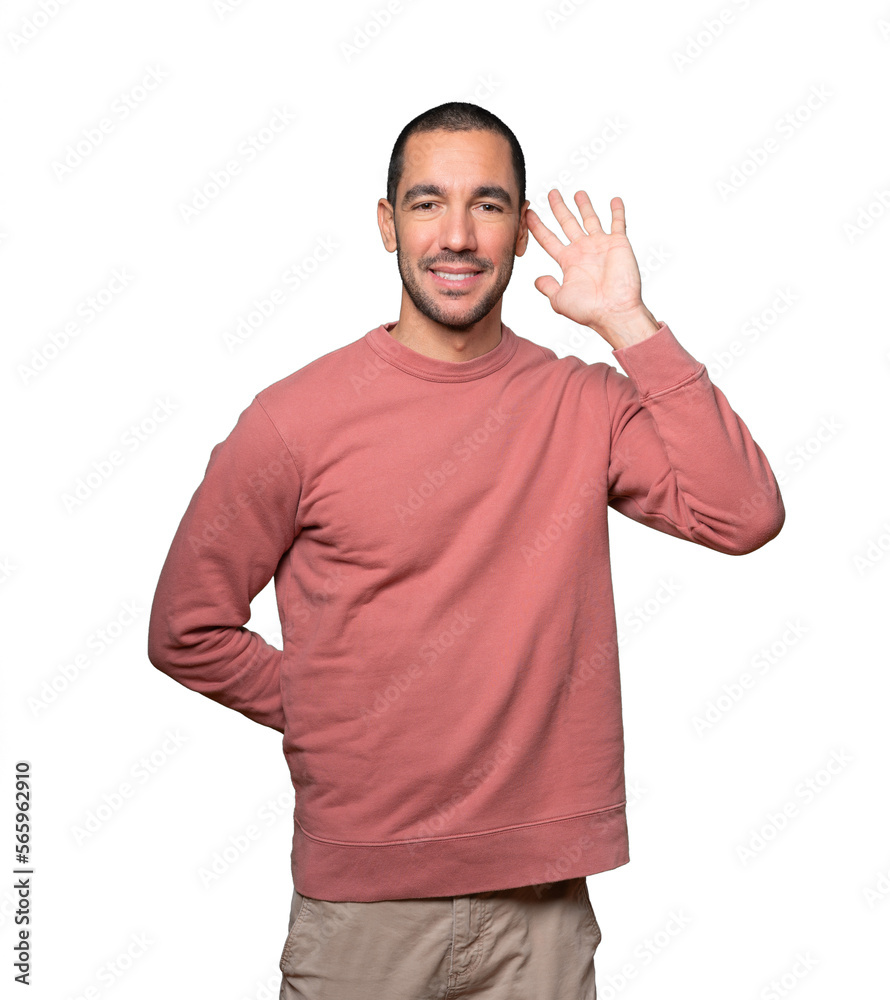 Happy young man smiling and making a gesture of trying to hear something Happy young man smiling and making a gesture of trying to hear something
