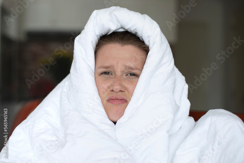 Portrait of young unhappy depressed girl, beautiful lazy lonely woman covering herself in blanket, suffering from depression with sad upset frustrated look at home in living room in early morning