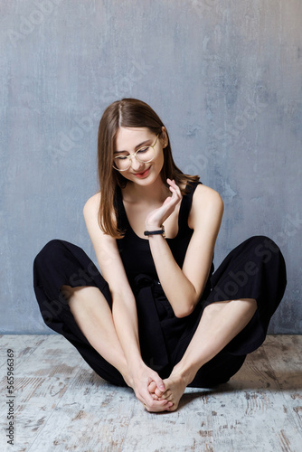 young confident happy woman sitting on floor in studio