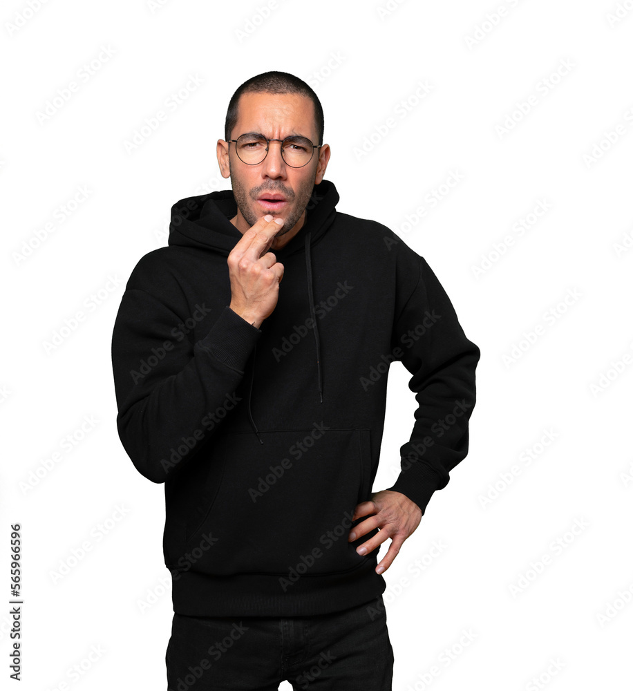 Concentrated young man making a gesture of distrust Concentrated young man making a gesture of distrust
