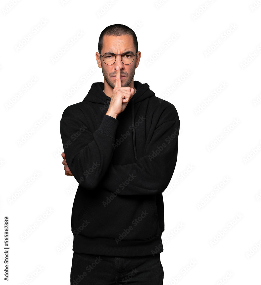 Serious young man asking for silence gesturing with his finger Serious young man asking for silence gesturing with his finger