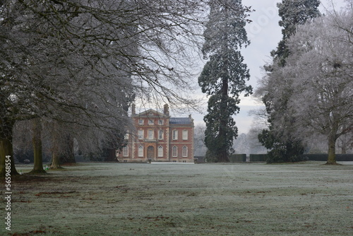 A view on a stately home through trees on a frosty winter day. Frosty park and grounds.  photo