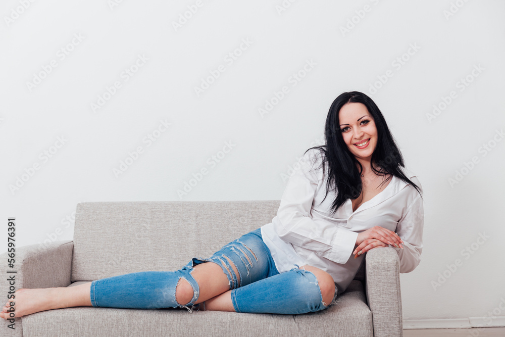 a woman in a free style sits in a room on a sofa a woman in a free style sits in a room on a sofa