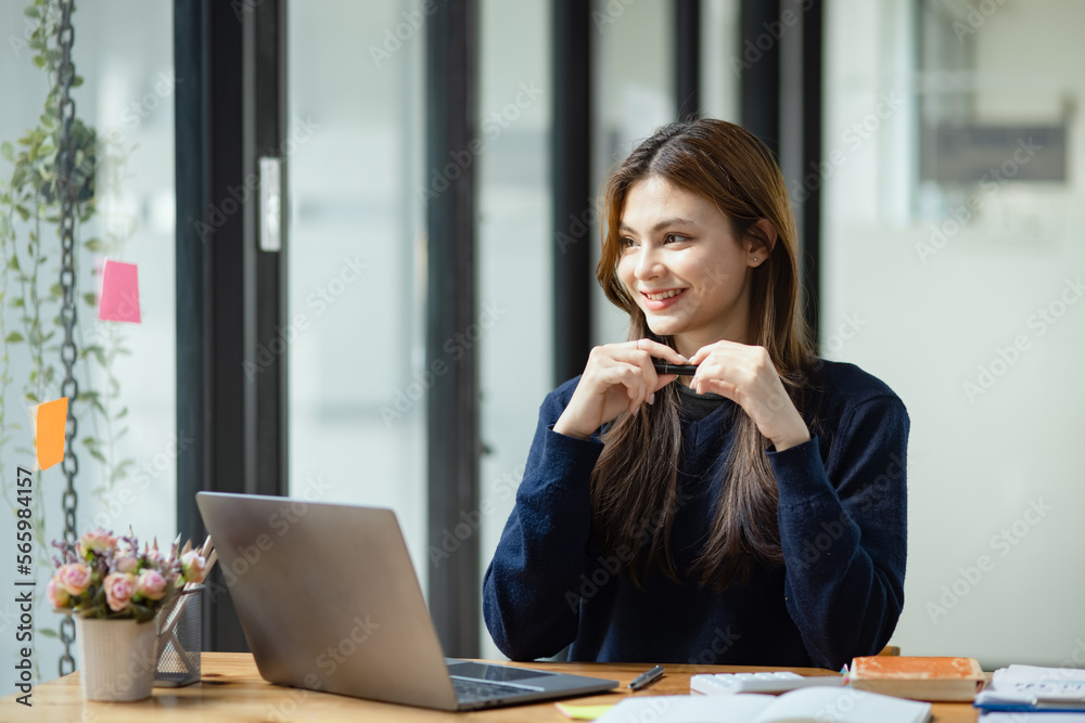 Happy smiling young asian business woman using laptop sitting at desk in the office, Company worker woman. Happy smiling young asian business woman using laptop sitting at desk in the office, Company worker woman.