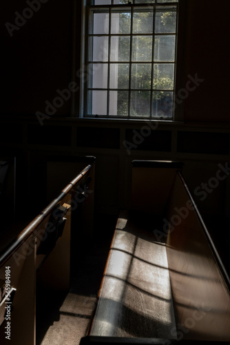 Light filtering through a church window with shadows on the pew