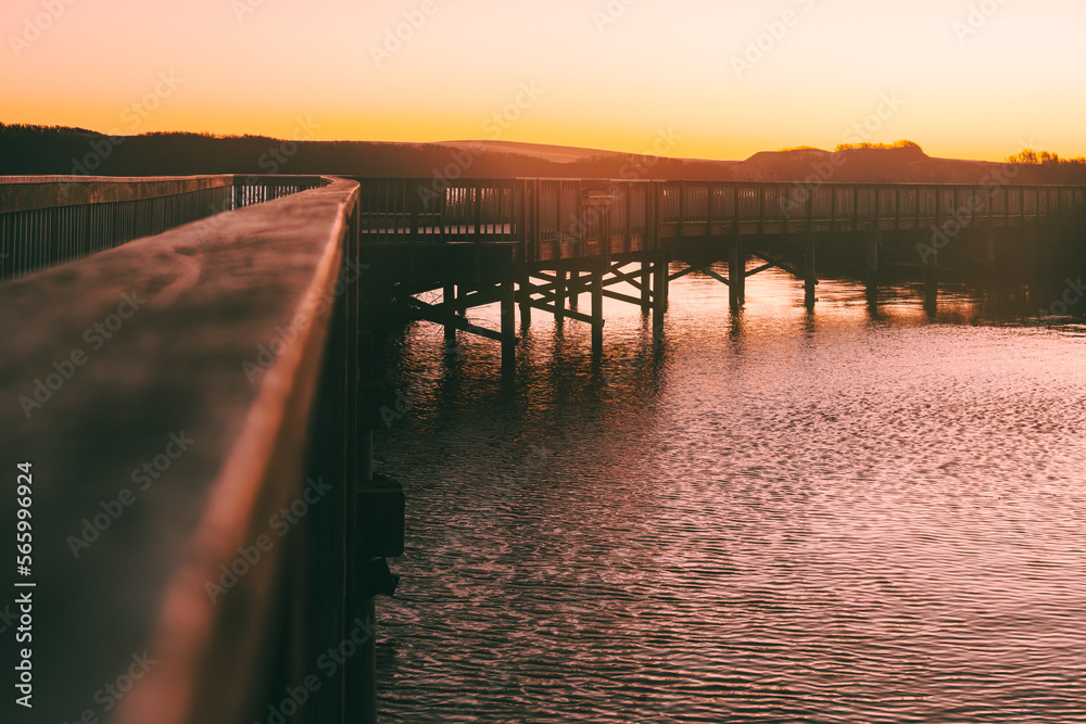 Pink sunset over the lake, and a long wooden boardwalk through the lake