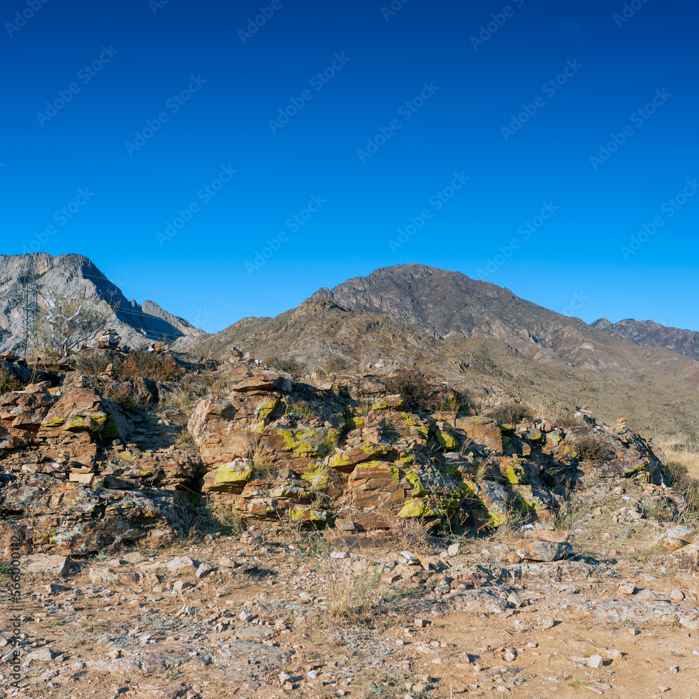 Power lines in the mountains next to stones with green moss on the rocks in Altai. Power lines in the mountains next to stones with green moss on the rocks in Altai.