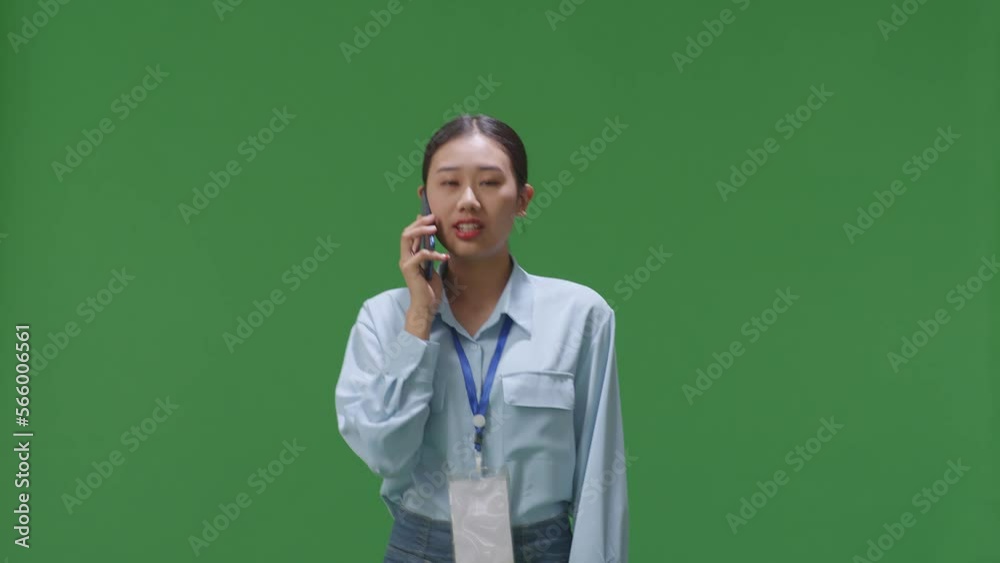Asian Business Woman Talking On Mobile Phone While Walking On Green Screen In The Studio
