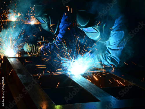 Workers wearing industrial uniforms and Welded Iron Mask at Steel welding plants, industrial safety first	
