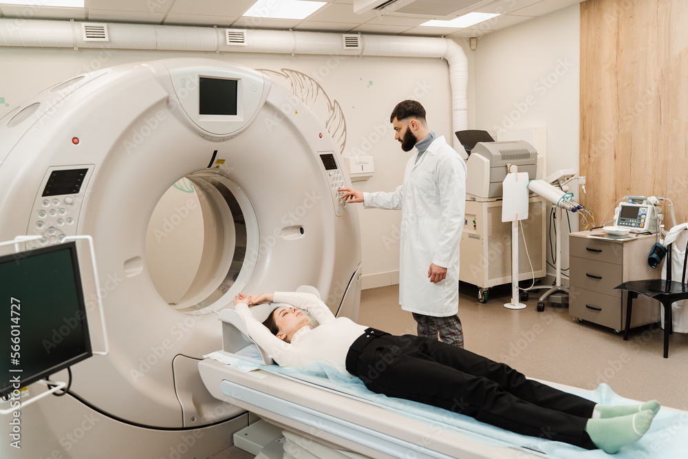 Girl patient is doing CT computed tomography x-ray scan of chest for examination of abdomen in a CT scanning room. CT scan of abdomen of woman in medical clinic. Girl patient is doing CT computed tomography x-ray scan of chest for examination of abdomen in a CT scanning room. CT scan of abdomen of woman in medical clinic.