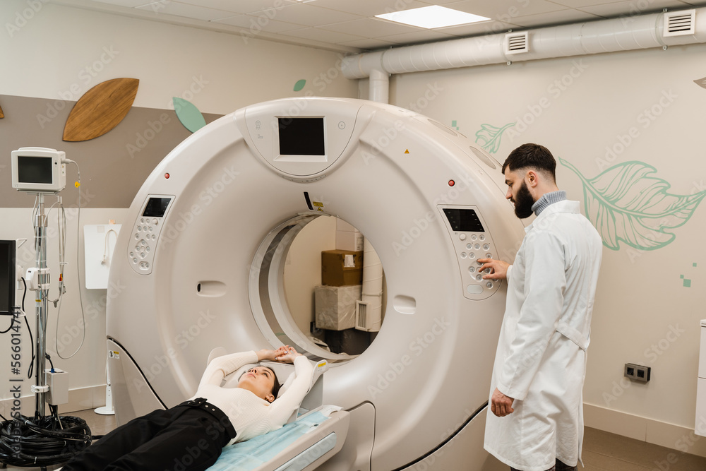 Girl patient is doing CT computed tomography x-ray scan of chest for examination of abdomen in a CT scanning room. CT scan of abdomen of woman in medical clinic. Girl patient is doing CT computed tomography x-ray scan of chest for examination of abdomen in a CT scanning room. CT scan of abdomen of woman in medical clinic.