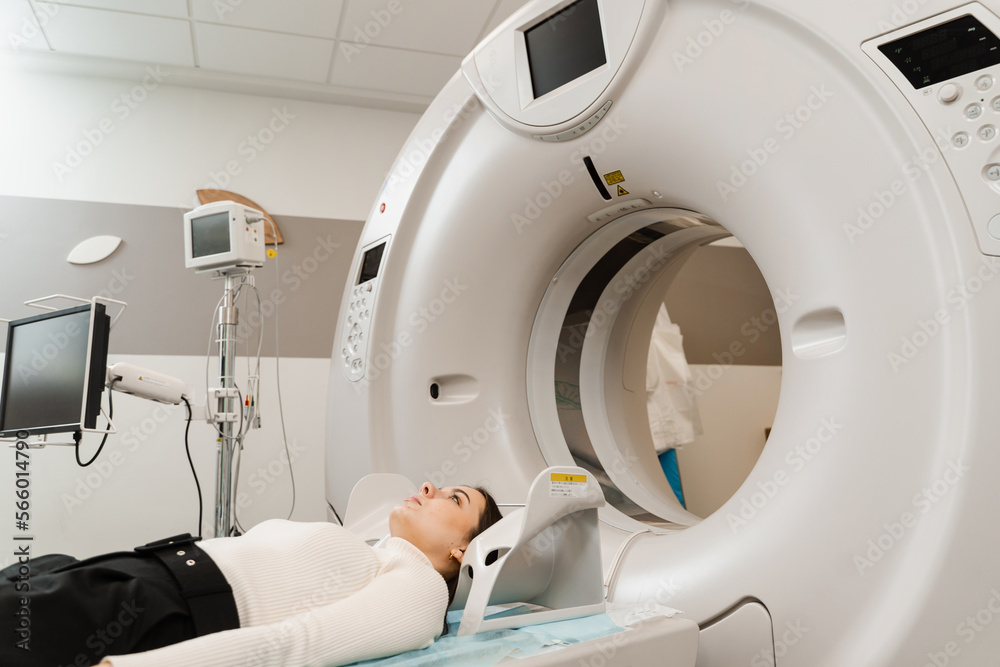 Girl patient is doing computed tomography x-ray examination of tumor in his head in a CT scan room. CT scan of brains of woman in medical clinic. Girl patient is doing computed tomography x-ray examination of tumor in his head in a CT scan room. CT scan of brains of woman in medical clinic.
