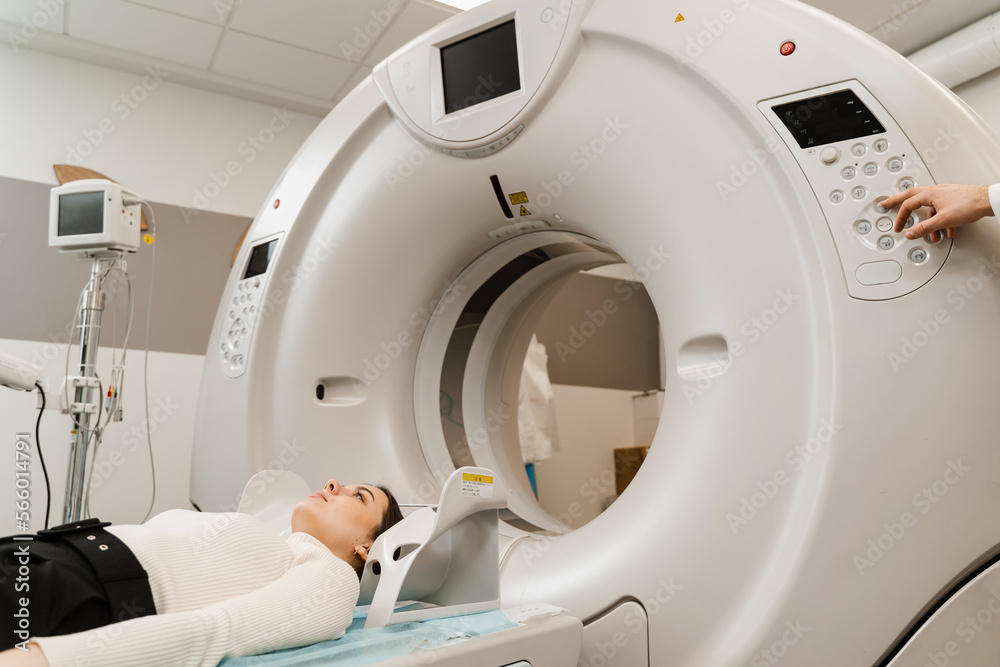 Girl patient is doing computed tomography x-ray examination of tumor in his head in a CT scan room. CT scan of brains of woman in medical clinic. Girl patient is doing computed tomography x-ray examination of tumor in his head in a CT scan room. CT scan of brains of woman in medical clinic.