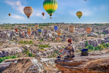 Man traveler vacations in beautiful destination in Goreme, Turkey. Fabulous Kapadokya with flying air balloons at sunrise, Anatolia