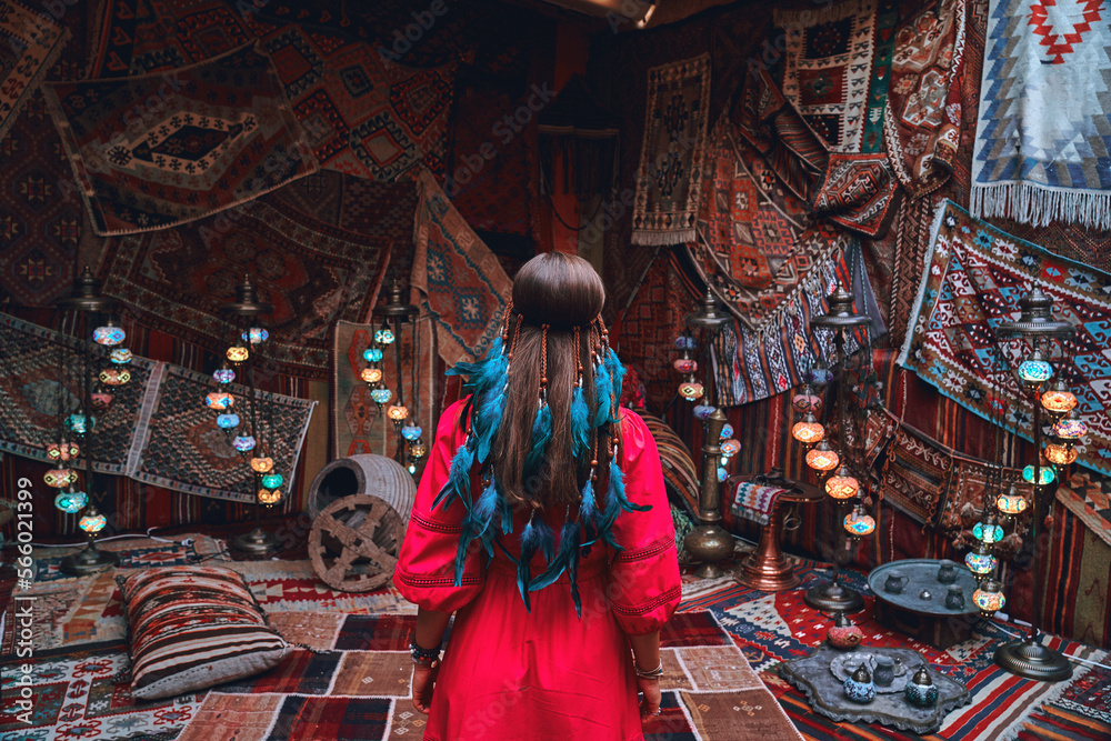 Obraz premium Boho girl traveler vacations at beautiful destination in Goreme, Nevsehir. Room with traditional Turkish carpets in Kapadokya, Anatolia
