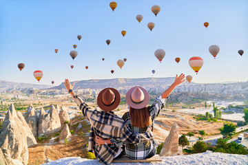 Couple travelers vacations together in beautiful destination in Goreme, Turkey. Fabulous Kapadokya with flying air balloons at sunrise, Anatolia