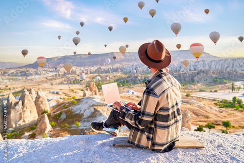 Inspired travel blogger guy working remotely and enjoying air balloons landscape