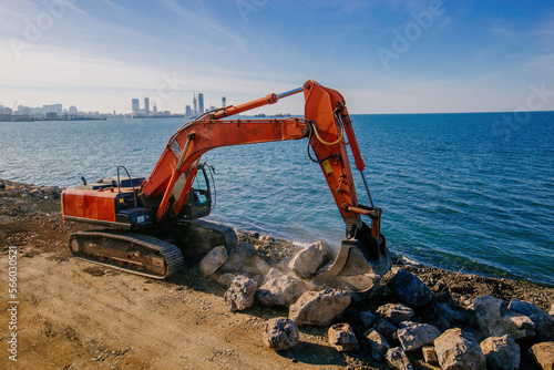 Excavator working on earthmoving at construction of new embankment