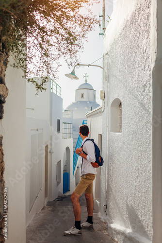 Santorini tourist man walking along narrow street in Fira, Greece among traditional white houses. Summer vacation © maryviolet