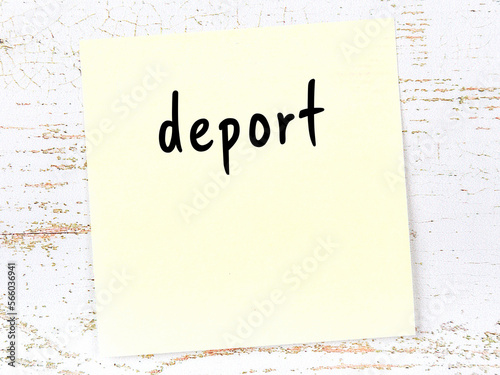 Fotografie Yellow sticky note on wooden wall with handwritten word deport