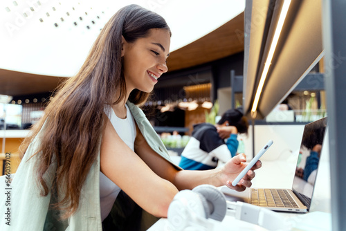 Free Download Beautiful smiling woman holding smartphone reading text message sitting at the cafe. Happy successful student studying, learning language sitting in modern library, online education concept  - GFXLoad