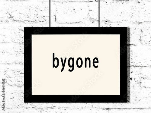 Фотография Black frame hanging on white brick wall with inscription bygone