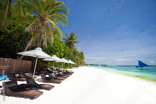Fototapeta Naklejka Na Ścianę i Meble -  Sun umbrellas and beach chairs on tropical beach with palm trees