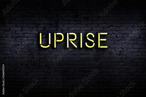 Night view of neon sign on brick wall with inscription uprise