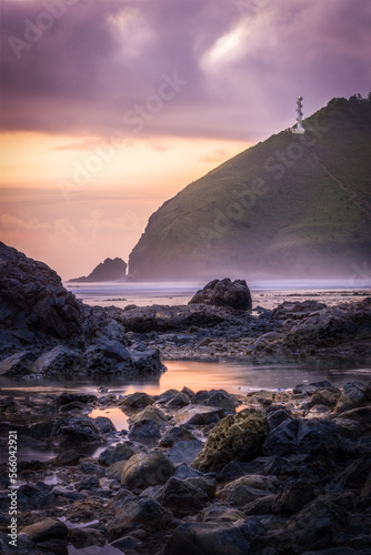 Purple sunrise on the beach with a view of a lighthouse on a hill in Baler  Philippines