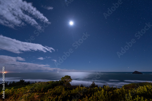 Moon shines brightly over the Pacific Ocean on a starry night at the Oregon Coast