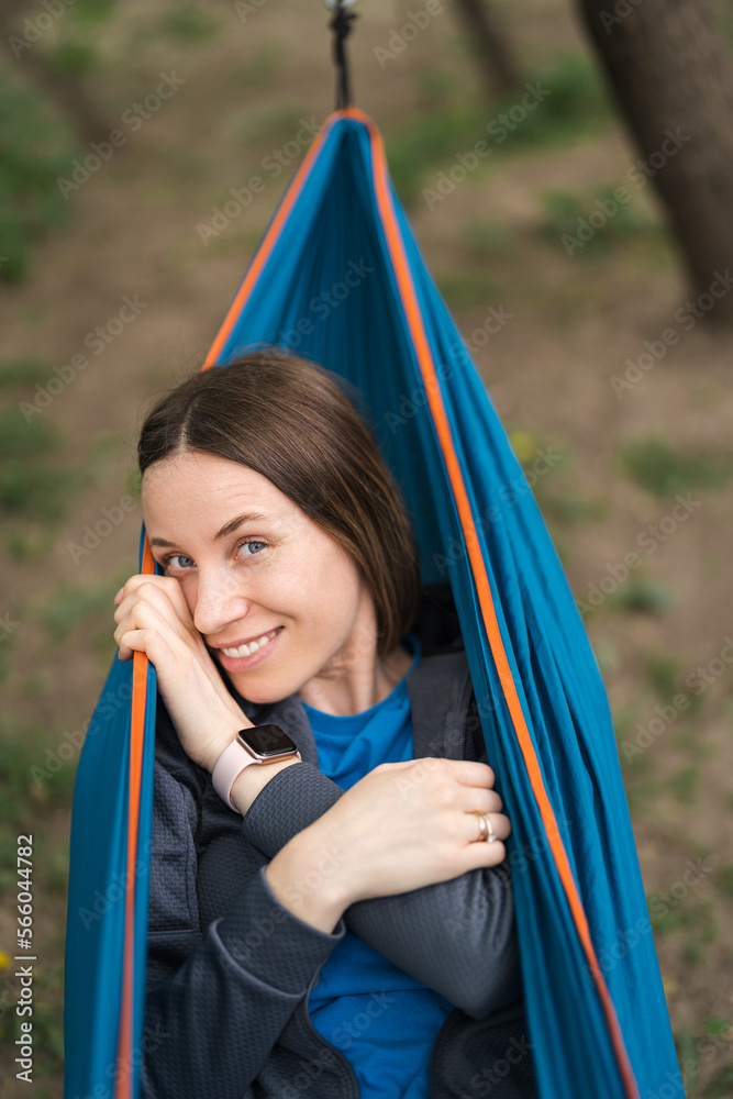 Smiling woman in casual clothes resting in a hammock outdoors in the weekend Smiling woman in casual clothes resting in a hammock outdoors in the weekend
