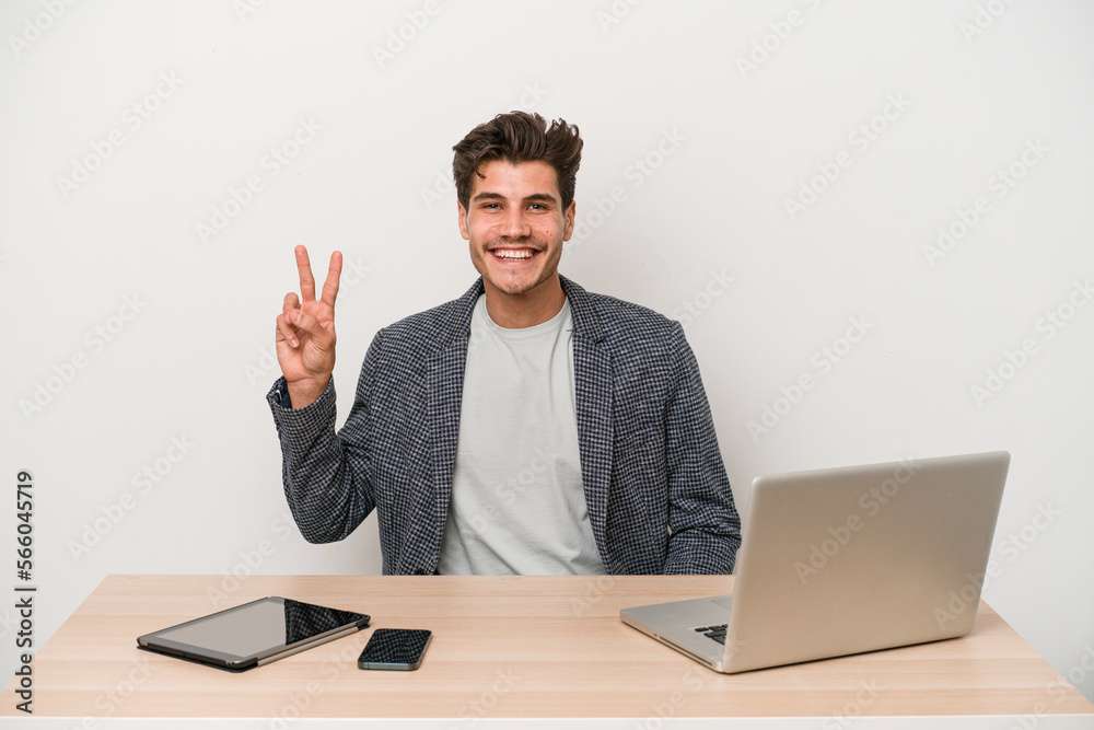 Young entrepreneur man working with a laptop isolated showing victory sign and smiling broadly. Young entrepreneur man working with a laptop isolated showing victory sign and smiling broadly.
