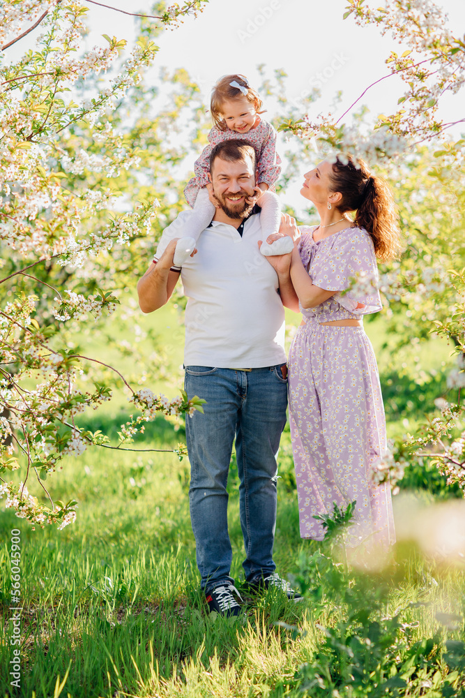 a mom and a dad with a baby daughter in a blooming spring garden. happy family. 