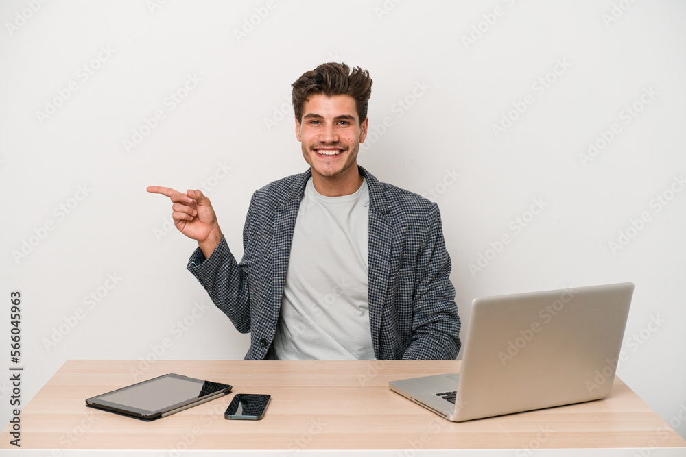 Young entrepreneur man working with a laptop isolated smiling cheerfully pointing with forefinger away. Young entrepreneur man working with a laptop isolated smiling cheerfully pointing with forefinger away.