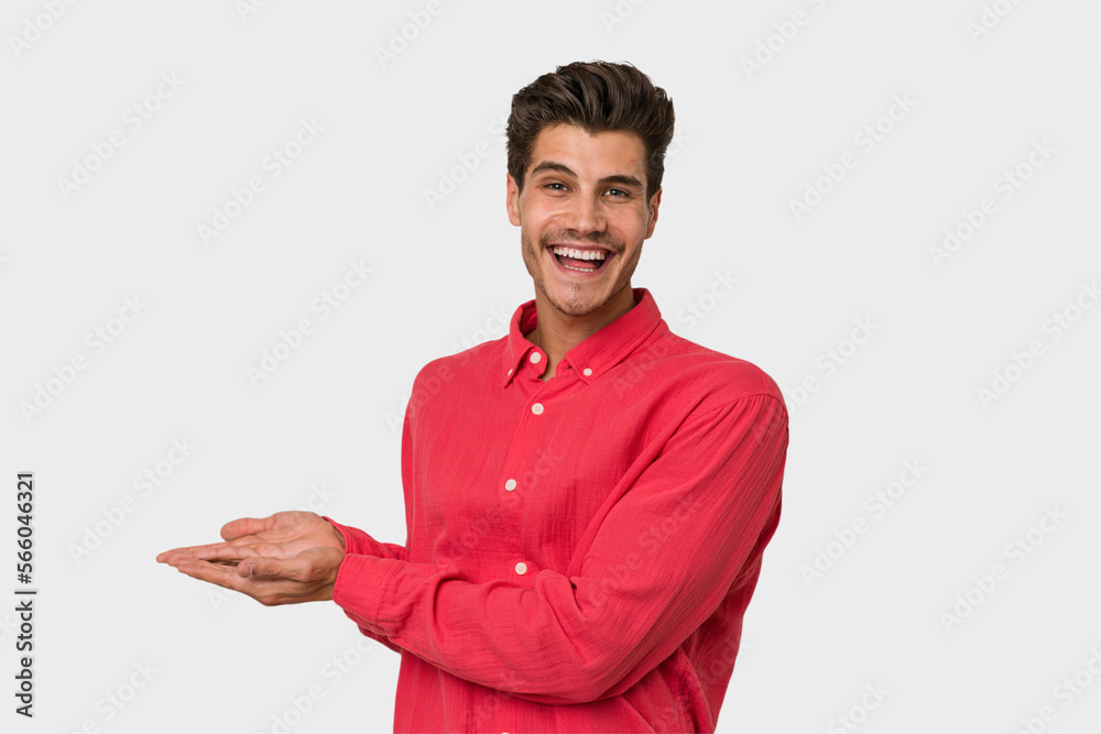 Young handsome caucasian man isolated on white background holding a copy space on a palm.