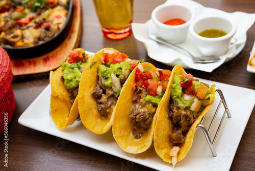 Mexican tacos with beef, guacamole and vegetables at plate