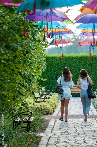 dziewczyny spacerujące pod kolorowymi parasolkami w parku