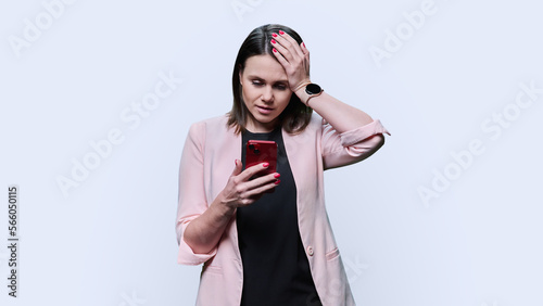 Sad shocked emotional young woman with smartphone in her hands