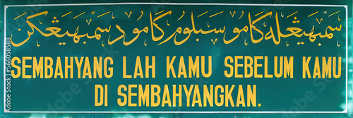 Muslim signboard on mosque for prayer call in Arabic calligraphy and Malay language photo