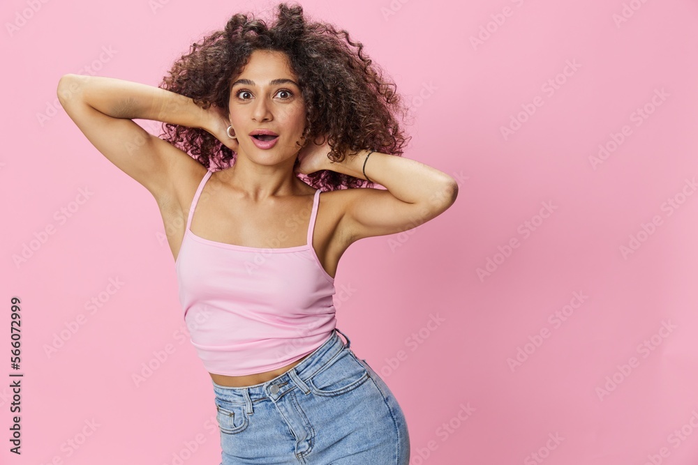 Woman with curly afro hair model poses on a pink background in a pink T-shirt, free movement and dance, look into the camera, smile with teeth and happiness, copy space Woman with curly afro hair model poses on a pink background in a pink T-shirt, free movement and dance, look into the camera, smile with teeth and happiness, copy space
