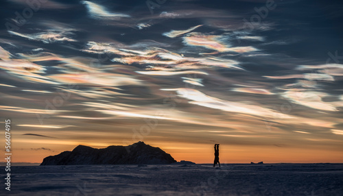 A woman does a handstand with polar Stratospheric clouds in the sky behind. photo