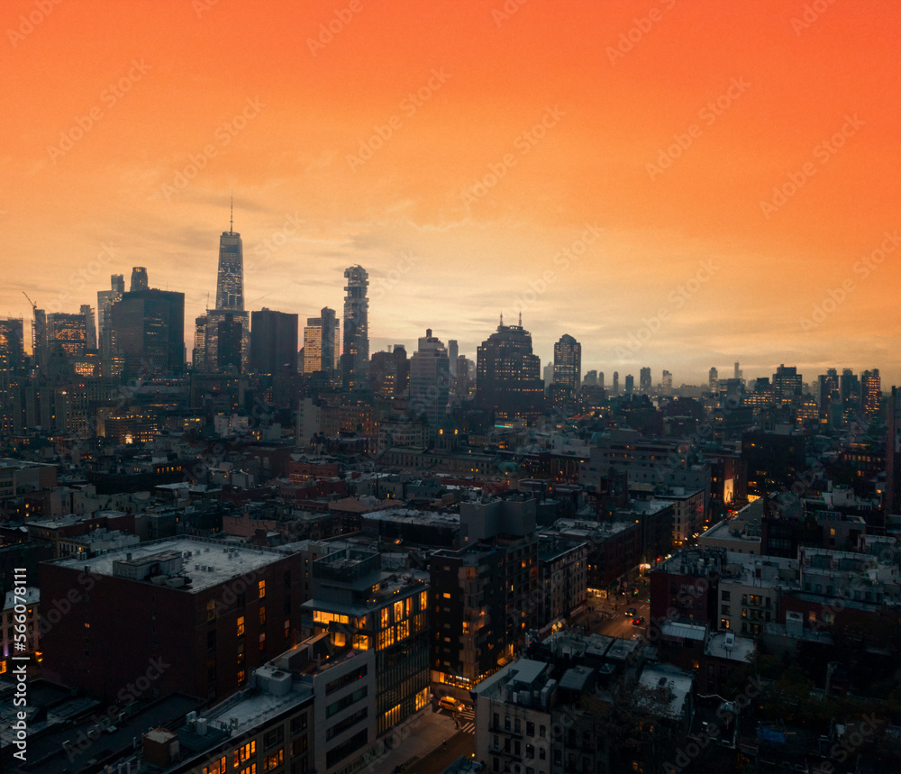 Crowded buildings of the New York City skyline with warm yellow orange sky above the downtown skyscrapers of Manhattan