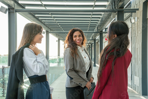 Three attractive businesswomen meet on the terrace of the business building for a pleasant chat.