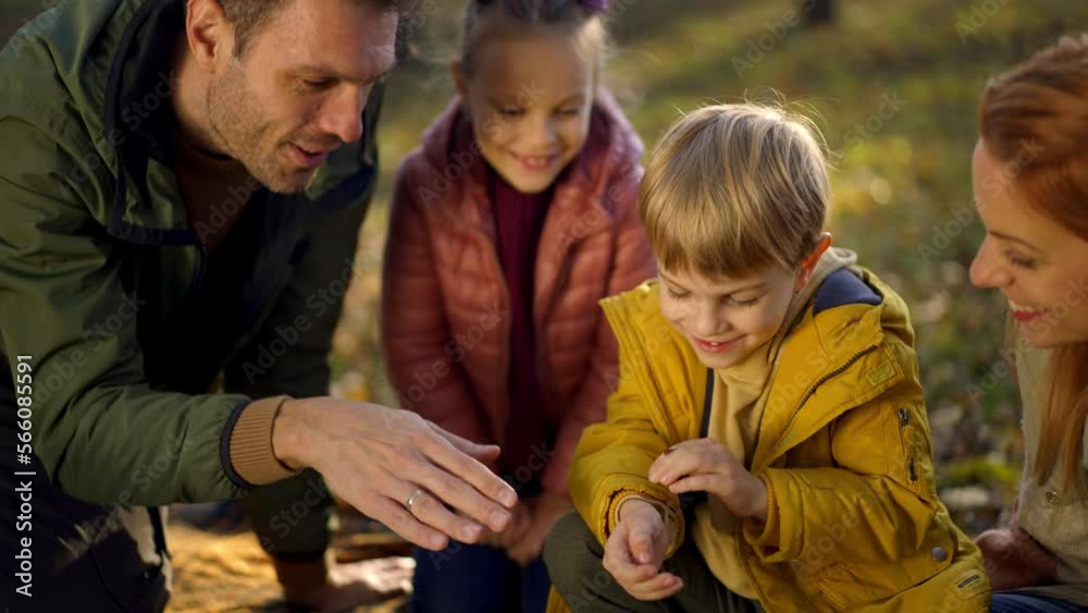 Close-up shot of a family with kids having picnic outdoors. Parents with two children having fun on a family picnic in the forest Close-up shot of a family with kids having picnic outdoors. Parents with two children having fun on a family picnic in the forest