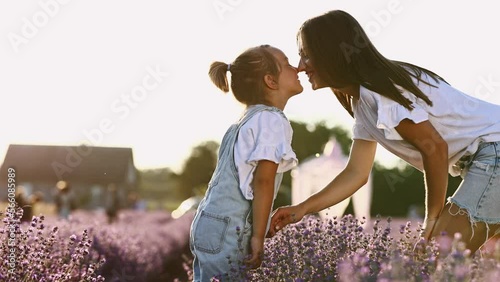 family day. young mom and little daughter enjoy relaxing in a field with lavender at sunset. A beautiful mother hugs and kiss child girl tightly. Maternal care and love for the child. mothers day.