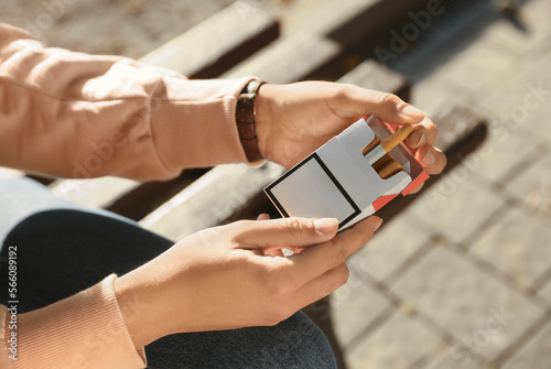 Quadro em tela Woman taking cigarette out of pack outdoors, closeup