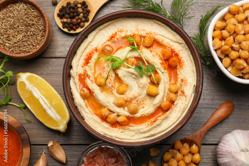 Delicious hummus with chickpeas and different ingredients on wooden table, flat lay